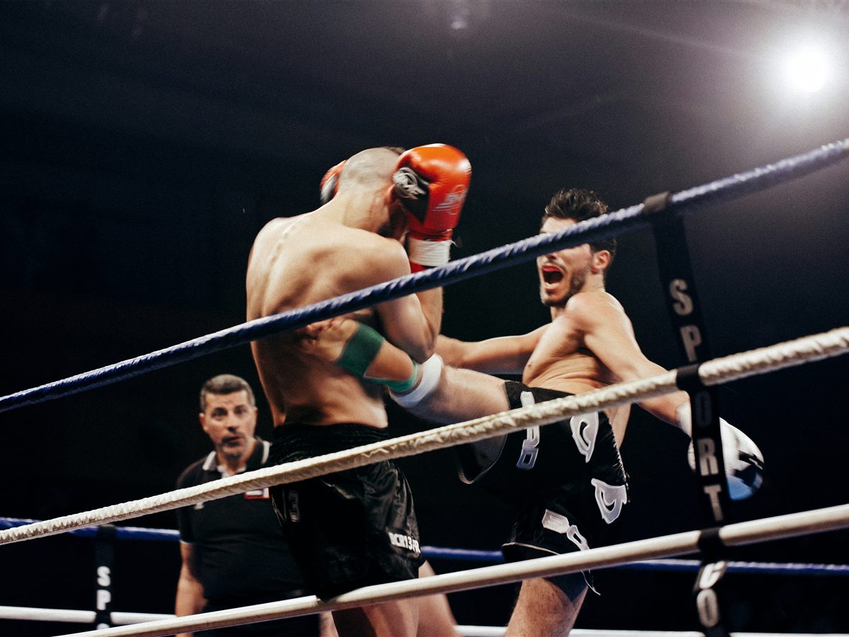 A kickboxer landing a body kick during a fight in the ring